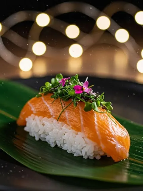 Lachs-Nigiri mit Kresse und Blüten auf einem Bananenblatt