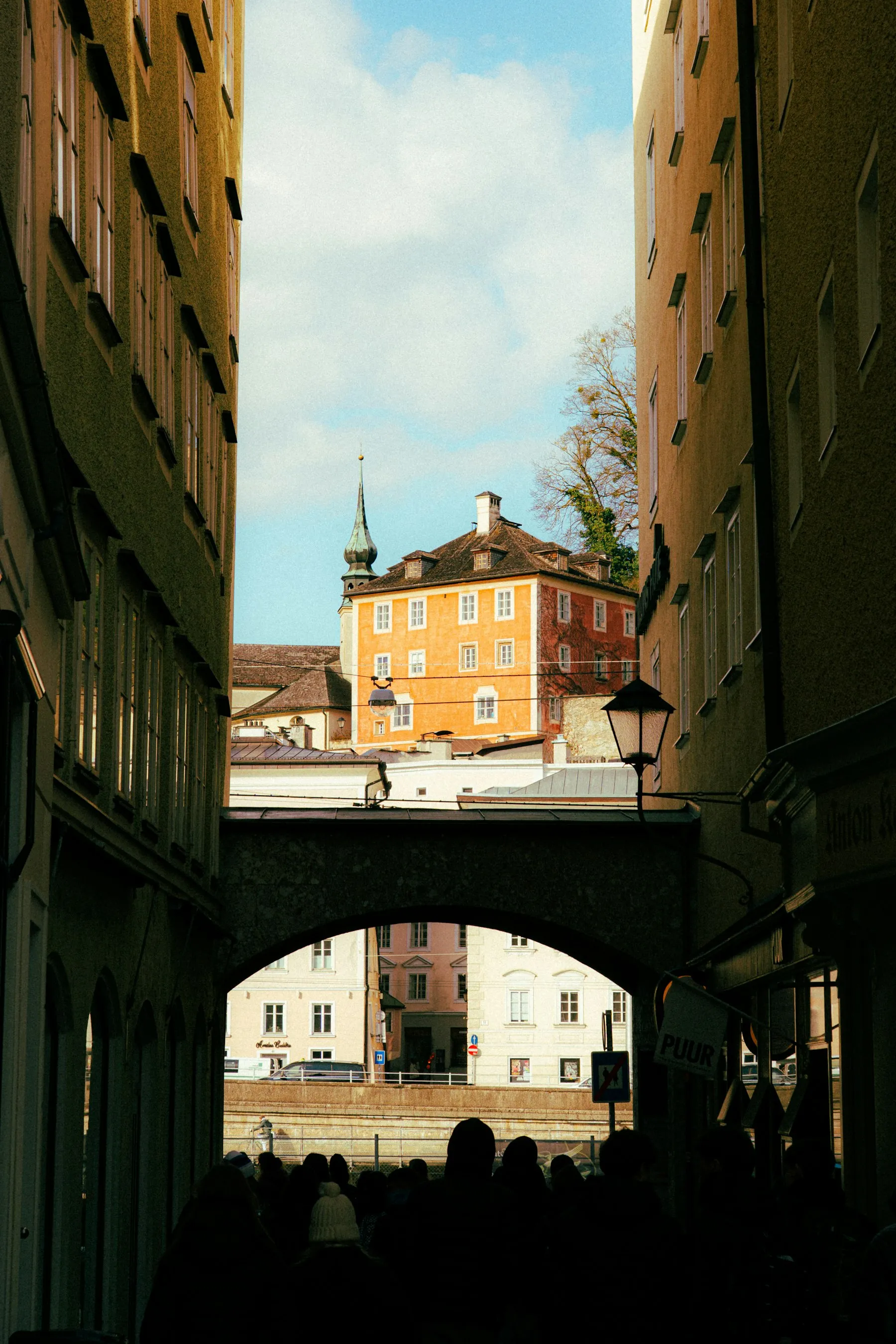 Schmale Gasse in der Salzburger Altstadt mit Torbogen im Gegenlicht